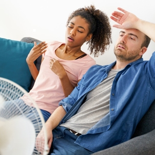 A couple sits in front of a fan