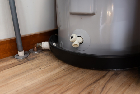 A electric water heater drain valve above the drain pan